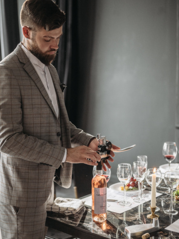 Man in gray plaid suit jacket holding wine glass